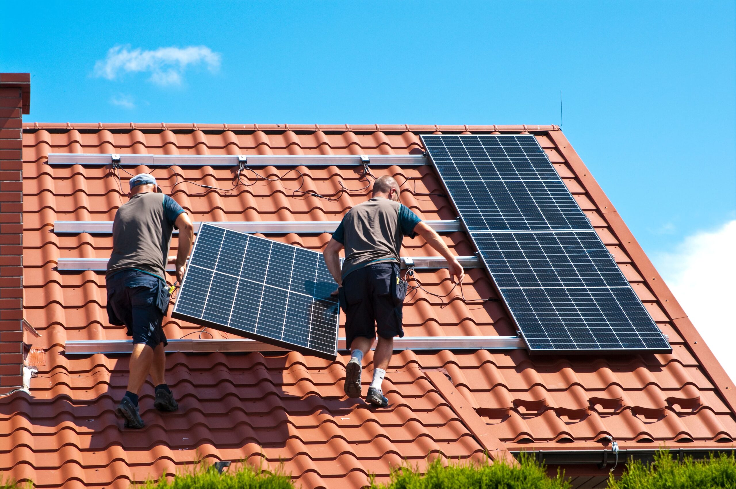 Techniciens installant des panneaux solaires sur le toit d'une maison, illustrant les différents types de panneaux solaires